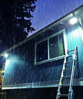Wasserdichter LED-Solarstrahler nach IP66, der bei starkem nächtlichem Regen ein Gebäude beleuchtet - Witterungsbeständigkeit und leistungsstarke Beleuchtung bei allen Wetterbedingungen garantiert