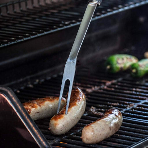 Grillgabel aus Stahl mit Würstchen auf dem Grill, perfekt zum Greifen und Anheben von Lebensmitteln, ohne sich zu verbrennen