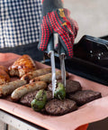 Grillgabel in praktischer Anwendung mit Würstchen, Hamburgern und Paprika auf dem Grill für perfektes Garen