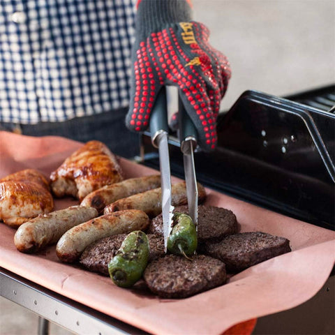 Grillgabel in praktischer Anwendung mit Würstchen, Hamburgern und Paprika auf dem Grill für perfektes Garen
